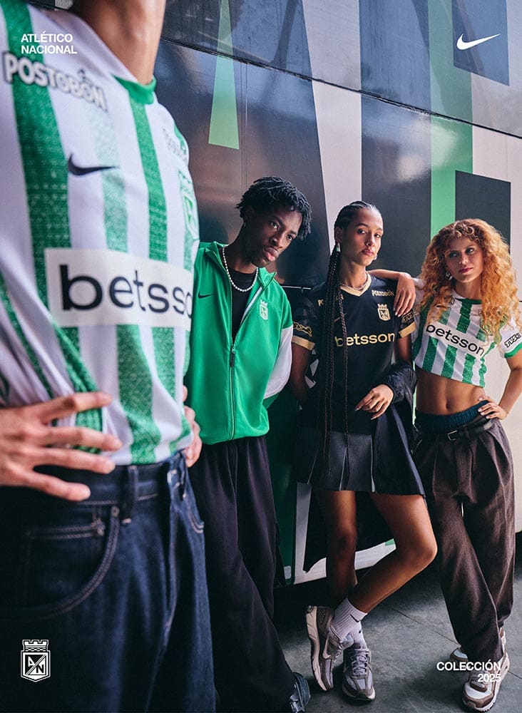Grupo de personas con camisetas, chaquetas y accesorios oficiales de Atlético Nacional 2025, reunidos frente a un bus.